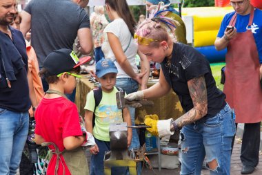 Zelenogradsk dövme Demircilik ve sanat sokak açık atölye bir çırak demirci olarak bilinmeyen çekici kız.