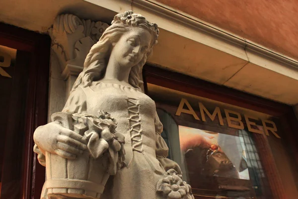 Escultura antigua de mujer joven cerca de la ventana de la tienda de recuerdos Ámbar en el centro histórico de Varsovia . — Foto de Stock