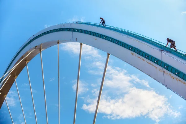 Two unknown men climbing of the arch of the iron bridge in the city center area. — Stock Photo, Image