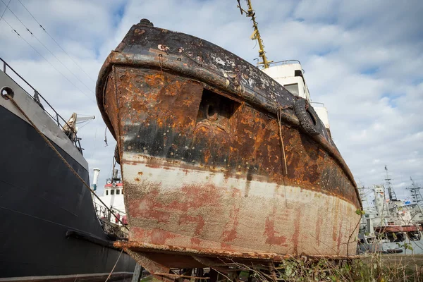 Rusty decommissioned marine ship that was left on the shore.