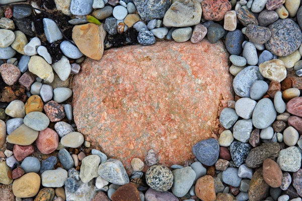 작은 돌로 둘러싸인 빨강과 분홍색의 큰 돌. — 스톡 사진