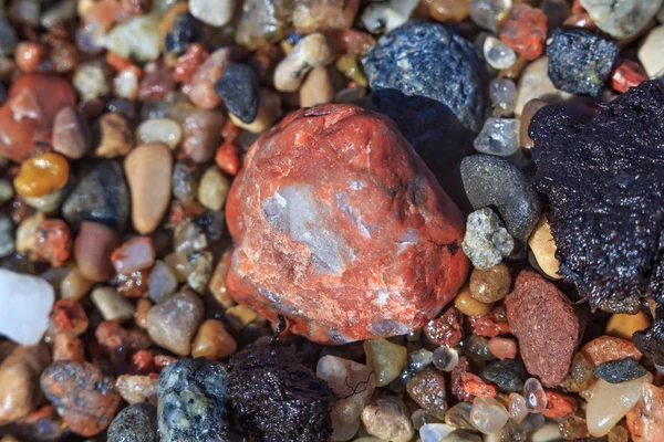 小红石作为湿海岸海卵石和沙的一部分. — 图库照片