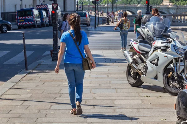 Neznámá mladá dívka v modrých džínách a tričko, které prochází dlažbu v centru Paříže. — Stock fotografie