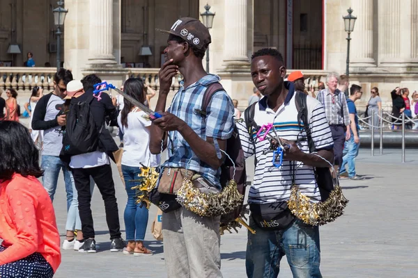 Two unknown young men selling souvenirs and baubles near the famous Louvre Palace in summer day. — Stock Photo, Image