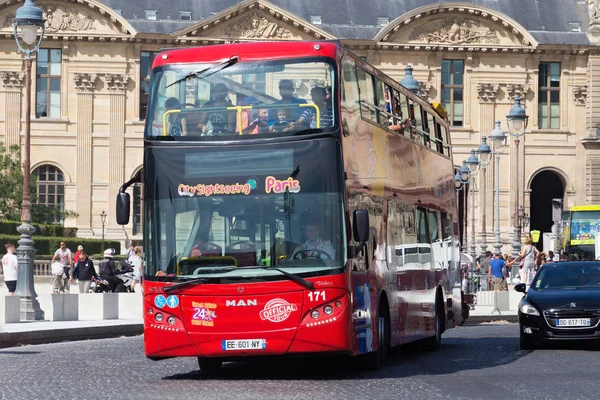 Grand bus touristique rouge avec les passagers sur la route près du célèbre palais du Louvre dans la journée d'été . — Photo