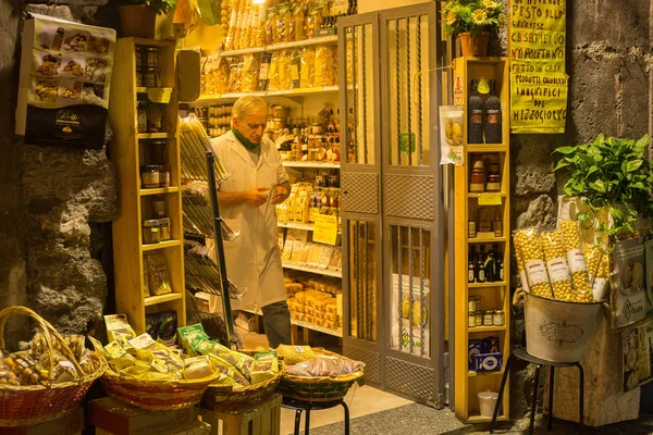 Vendedor napolitano na entrada da loja com uma comida tradicional italiana no centro de Nápoles à noite . — Fotografia de Stock