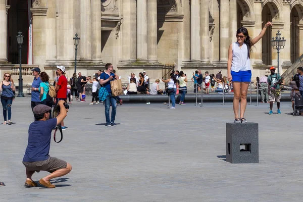 Unknown young woman standing on the special pedestal and posing for a photo near the famous Louvre Palace — Stock Photo, Image