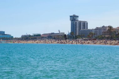 BARCELONA, İspanya - 15 Mayıs 2017: Bilinmeyen insanlar Barcelona şehir plajında dinleniyor ve arka plandaki modern binalara bakıyorlar.