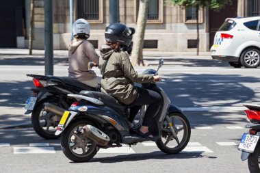 BARCELONA, SPAIN - 16 Mayıs 2017: Güneşli bir günde Barcelona 'nın merkezinde bilinmeyen kadınlar scooterlara biniyor.