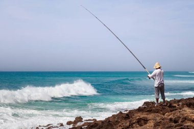 Güneşli bir günde Atlantik Okyanusu kıyısında bilinmeyen bir balıkçı..