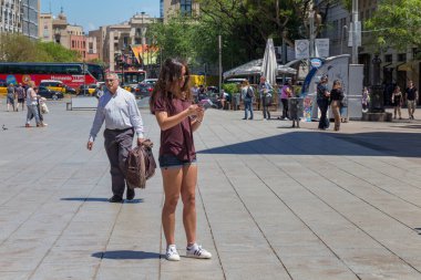 BARCELONA, SPAIN - 15 Mayıs 2017: Güneşli bir günde Barcelona 'nın tarihi merkezinde Placa Nova caddesinde (Barselona Katedrali yakınlarında) cep telefonlu bilinmeyen çekici kadın.