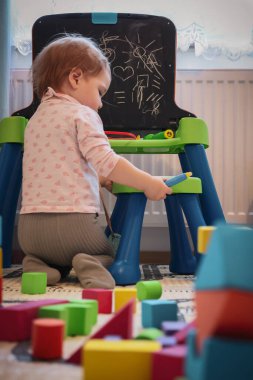 Bebek karatahta sehpasında oyuncaklarla oynuyor.