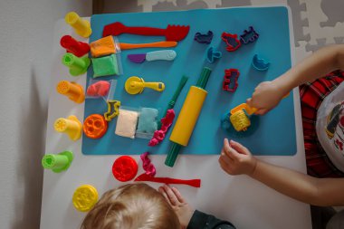 Çocuklar hamuru modelliyor ve renkli kesiciler ve aletler kullanıyor..