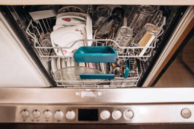 Mutfakta temiz tabaklar, bardaklar ve bardaklarla dolu bulaşık makinesini aç. Ev aletleri konsepti, temizlik ve modern yaşam tarzı.