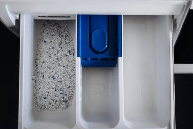 Close-up of washing machine dispenser drawer with laundry detergent.