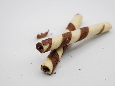 Çikolata şeritleriyle süslenmiş gevrek gofret tüplerini kapatın. Lezzetli tatlı ve beyaz üzerine izole edilmiş atıştırmalık konsepti.