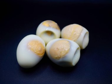 Makro haşlanmış organik tavuk yumurtası, sarısı görünüyor, siyah yüzeyde izole edilmiş. Yemek fotoğrafçılığı, diyet menüsü, organik protein ve sağlıklı yaşam tarzı kavramları için ideal.