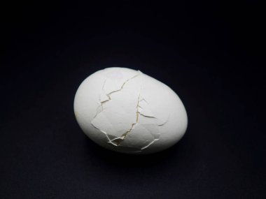 Haşlanmış tavuk yumurtasının yüksek çözünürlüklü fotoğrafı. Koyu arka planda kırılmış kabuğu var. Yemek, beslenme, diyet ve doğal protein kavramları için mükemmel.