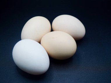 Yüksek çözünürlüklü yakın plan fotoğraf, arka planda dört çiftlik taze tavuk yumurtası. Organik gıda, protein besinleri, kümes hayvanları ve doğal bileşenler için mükemmel.