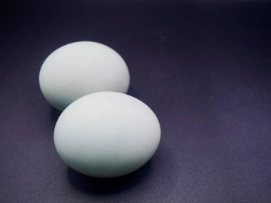 İki organik ördek tuzlu yumurtası siyah yüzeye izole edilmiş mutfak teması, yemek malzemeleri ve otantik Asya mutfağı için uygun.