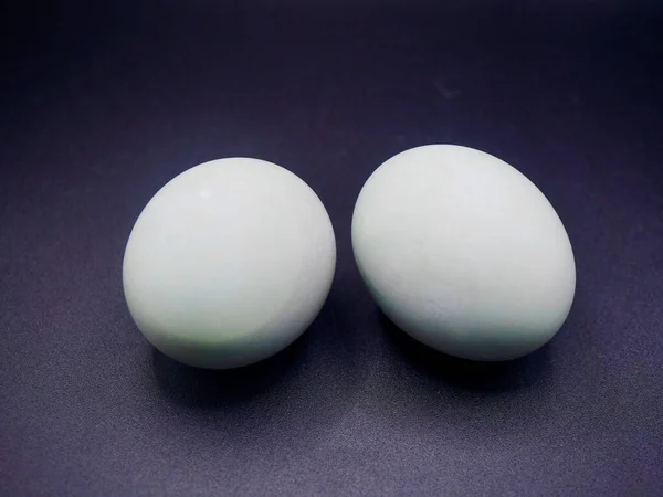 Doğal kabuk dokusuna sahip iki tuzlu ördek yumurtasının yüksek kaliteli fotoğrafı, koyu bir arka planda izole edilmiş, mutfak ve yemek kavramları için mükemmel.