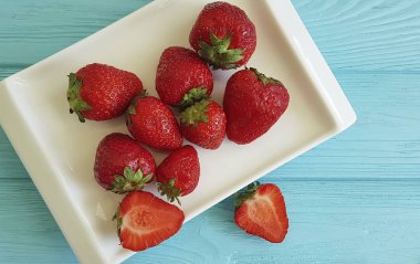 çilek mavi ahşap arka plan üzerine bir tabak içinde