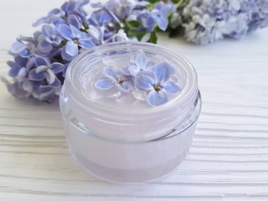 Beyaz ahşap zemin üzerinde kozmetik krem Lila çiçek