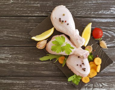 çiğ tavuk ayakları üzerinde ahşap arka plan, havuç, limon, maydanoz, biber