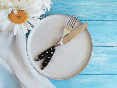 papatya, tabak, çatal, bıçak mavi ahşap arka plan üzerinde