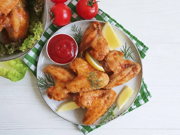fried wings, ketchup, lemon on a wooden background