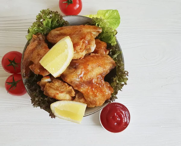 fried wings, salad on a wooden background