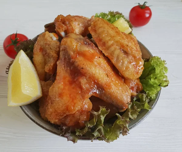 fried wings, salad on a wooden background