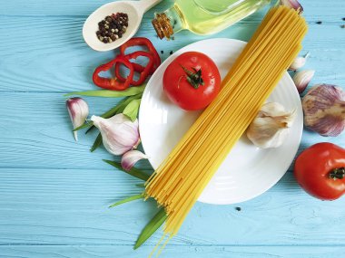 Spagetti, domates, sarımsak plaka üzerinde mavi bir ahşap arka plan