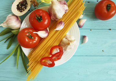 Spagetti, domates, sarımsak plaka üzerinde mavi bir ahşap arka plan