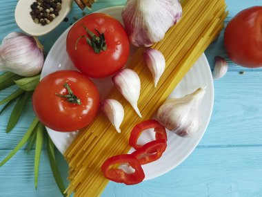 Spagetti, domates, sarımsak plaka üzerinde mavi bir ahşap arka plan