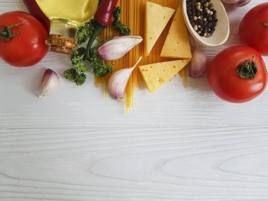 Spagetti, domates, sarımsak, biber, tereyağı, peynir ahşap arka plan üzerinde