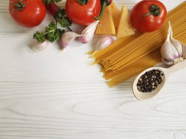 Spagetti, domates, sarımsak, biber, tereyağı, peynir ahşap arka plan üzerinde