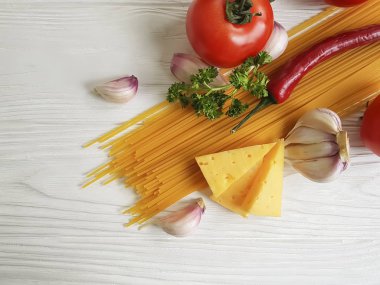 Spagetti, domates, sarımsak, biber, tereyağı, peynir ahşap arka plan üzerinde