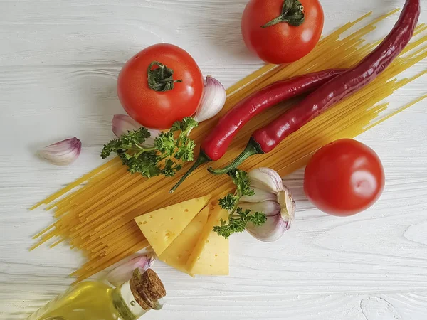 Spagetti, domates, sarımsak, biber, tereyağı, peynir ahşap arka plan üzerinde