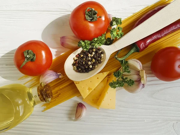 Spagetti, domates, sarımsak, biber, tereyağı, peynir ahşap arka plan üzerinde