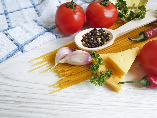 Spagetti, domates, sarımsak, biber, tereyağı, peynir ahşap arka plan üzerinde