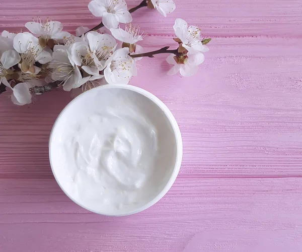 pembe ahşap arka plan üzerinde kozmetik krem çiçek açması kiraz