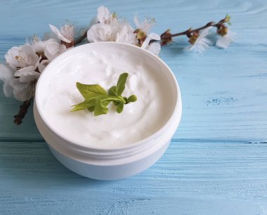 Mavi ahşap arka plan üzerinde kozmetik krem çiçek açması kiraz