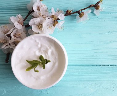 Mavi ahşap arka plan üzerinde kozmetik krem çiçek açması kiraz