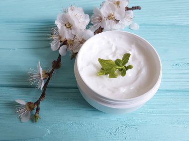 Mavi ahşap arka plan üzerinde kozmetik krem çiçek açması kiraz