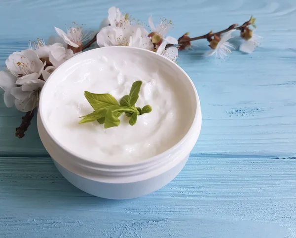 Mavi ahşap arka plan üzerinde kozmetik krem çiçek açması kiraz