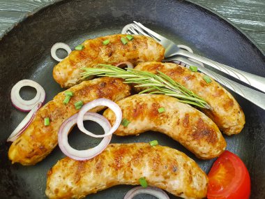 Kızarmış sosis tava, domates, soğan, siyah eski ahşap zemin üzerinde