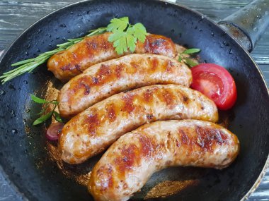 Kızarmış sosis tava, domates, soğan, siyah eski ahşap zemin üzerinde