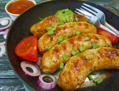 Kızarmış sosis tava, domates, soğan, siyah eski ahşap zemin üzerinde