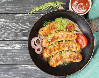 Kızarmış sosis tava, domates, soğan, siyah eski ahşap zemin üzerinde